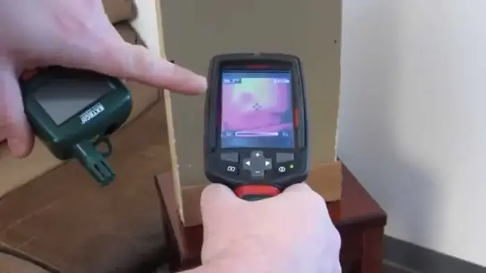 Thermal imaging camera held up to a wall to find hidden moisture