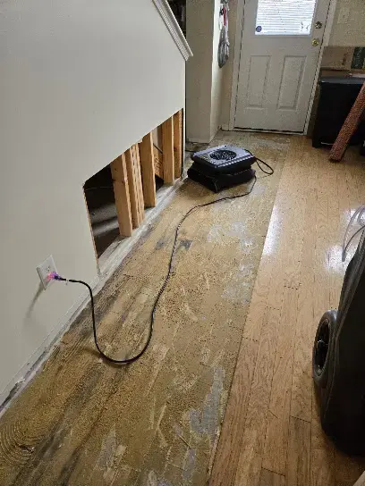 Air mover drying a hallway floor where the lower wall was opened up