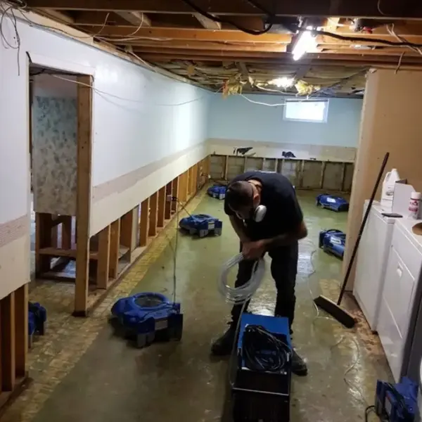 Technician setting drying equipment in a gutted lower level
