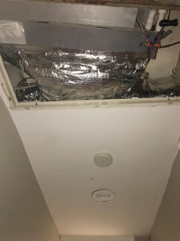 Air handler above an opened ceiling panel where a condensate line runs