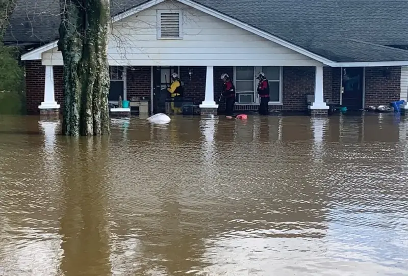 Brick ranch home surrounded by brown flood water after heavy rain
