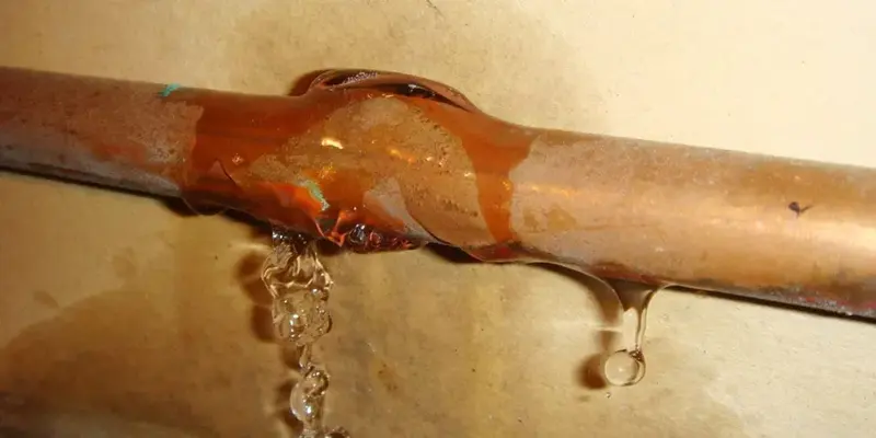 Split copper pipe dripping water after a hard freeze